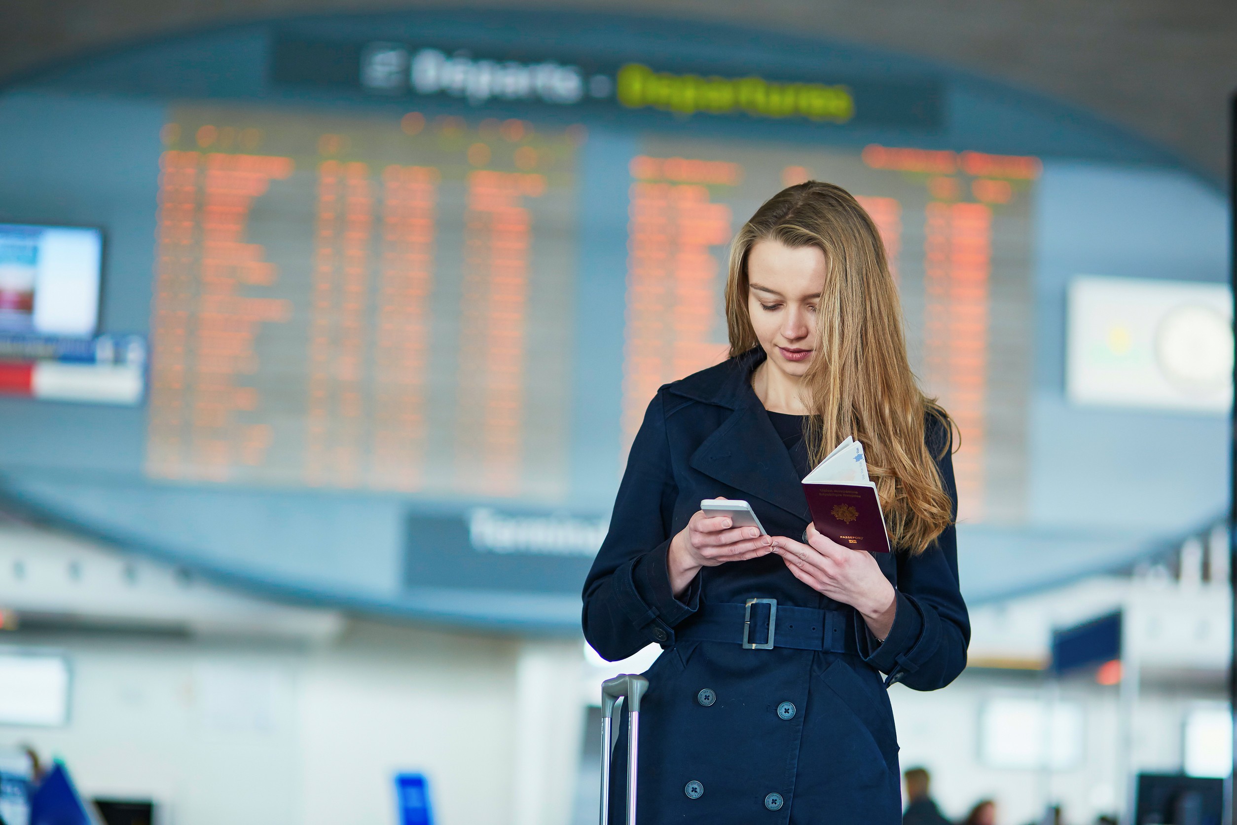 Young Woman In International Airport Near The Flight Information Board Holding